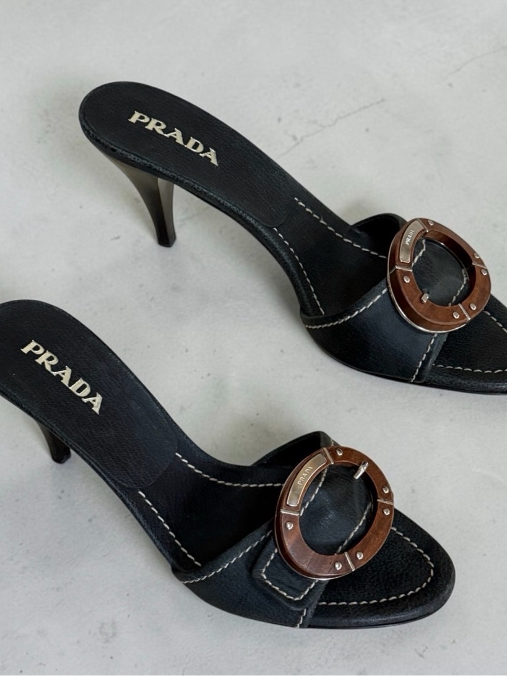 Prada Black Leather Open-Back Heeled Mules with Brown Circular Buckle